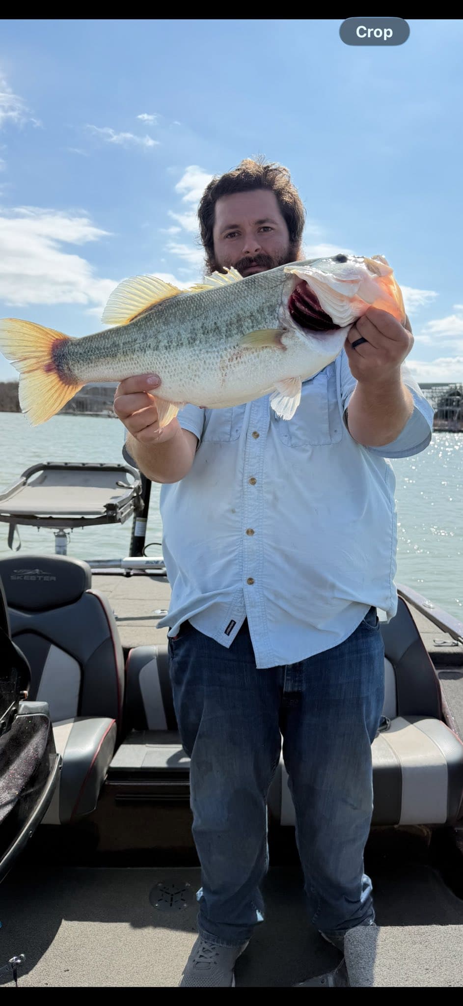 Client holding a largemouth bass on the boat